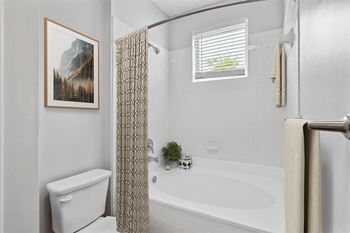 a bathroom with a white toilet next to a bathtub with a shower curtain Two Addison Place, Pooler GA  at Two Addison Place, Pooler, 31322